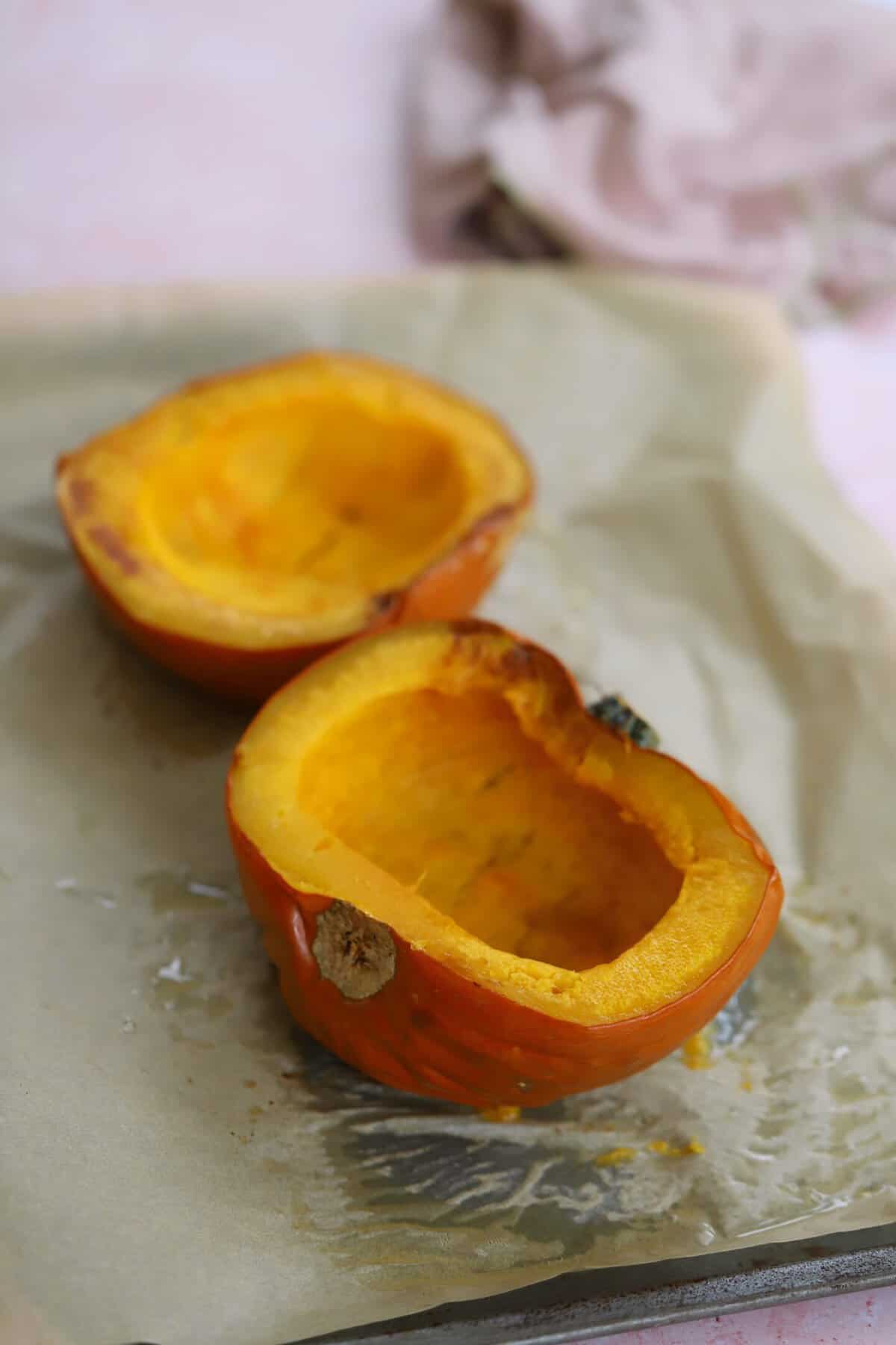 The baked pumpkin halves cooling on a baking sheet.