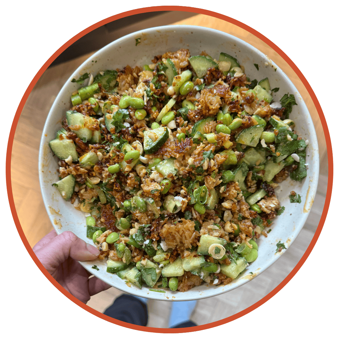 A hand holding a bowl of crispy rice salad.